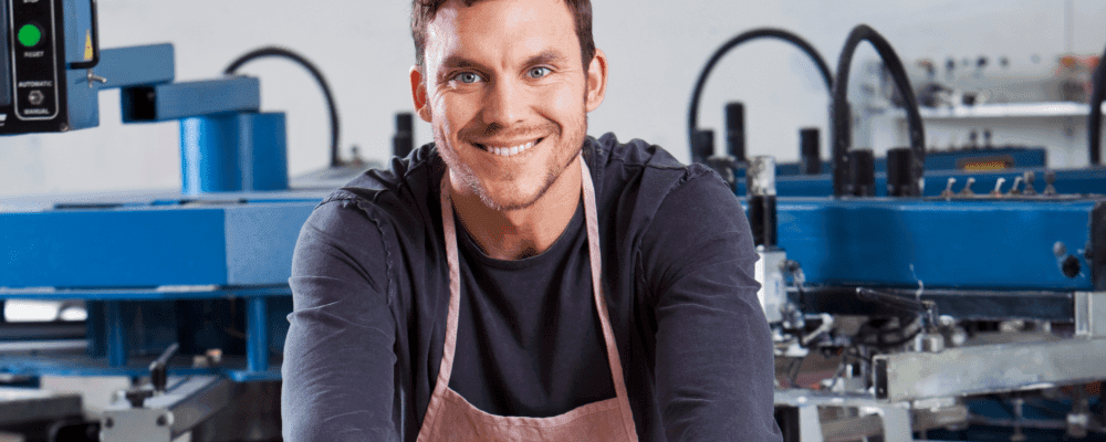 Auf diesem Bild ist eine Person zu sehen, die eine Ausbildung zum/r Medientechnologen/-technologin im Siebdruck absolviert. Dieser Beruf umfasst die Herstellung von Druckvorlagen und das Bedrucken von Oberflächen mit Hilfe einer Siebdruckpresse. Die Person sorgt dafür, dass die Vorlagen richtig hergestellt werden und die Oberflächen sauber und professionell bedruckt werden.
