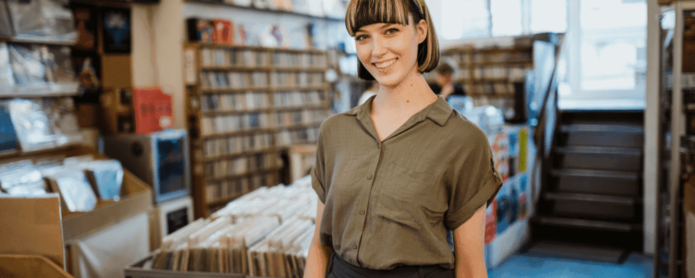 Auf diesem Bild ist eine Person zu sehen, die eine Ausbildung zum/r Musikfachhändler/in ausübt. Diese Person verkauft verschiedene Musikinstrumente und Zubehör an Kunden. Um erfolgreich zu sein, muss sie über ein gutes Wissen der Instrumente und des Marktes verfügen.