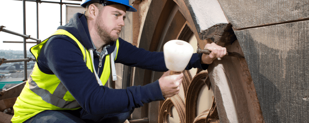 Auf diesem Bild ist eine Person zu sehen, die eine Ausbildung zum/r Naturwerksteinmechaniker/in absolviert. Dieser Beruf umfasst die Bearbeitung und Pflege von Naturwerksteinen aller Art. 