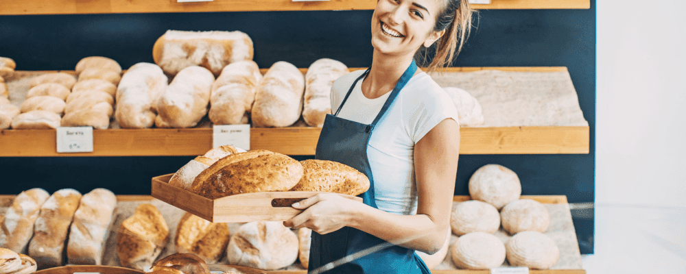 Dies ist ein Foto von einer Person, die eine Ausbildung zum/r Bäckereifachverkäufer/in absolviert. Die Person ist damit beschäftigt, Backwaren an Kunden zu verkaufen.