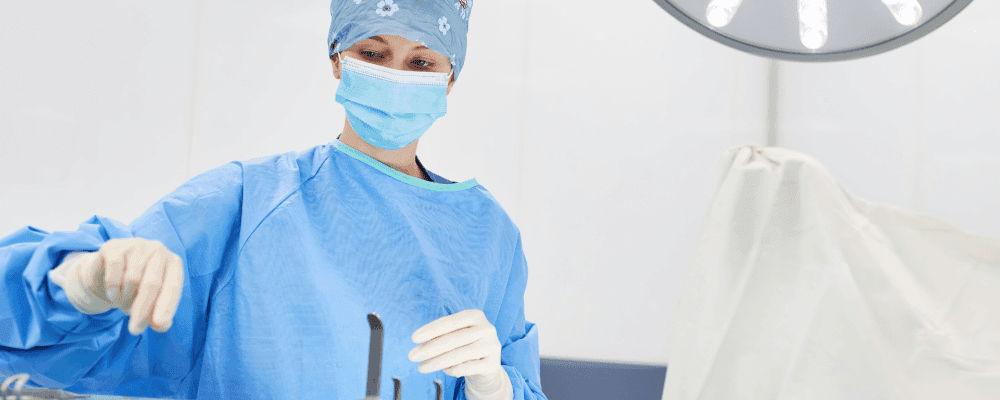 Auf diesem Bild ist eine Person zu sehen, die eine Ausbildung zum/r chirurgischen Assistenten/in absolviert. Dieser Beruf ist sehr wichtig, da er dafür sorgt, dass Operationsverfahren reibungslos ablaufen können. Die Person auf dem Bild ist damit beschäftigt, Instrumente und andere Gegenstände für eine bevorstehende Operation vorzubereiten.