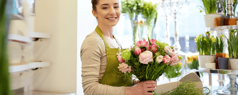 Dies ist ein Bild von einer Person, die eine Ausbildung zum/r Florist/in absolviert. Die Person sieht sehr professionell aus und man kann erkennen, dass sie mit Blumen arbeitet.