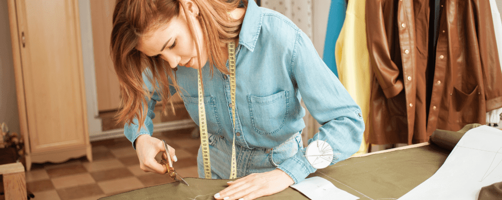 In der Ausbildung zum/r Änderungsschneider/in lernt man, dass Kleidungsstücke perfekt sitzen und aussehen. Die Person auf dem Bild ist sehr konzentriert bei der Arbeit und sorgfältig dabei, damit das Ergebnis perfekt ist.